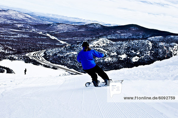 A female snowboarder carves in freshly groomed corduroy in New Hampshire.