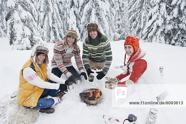 Austria  Salzburg  Men and women sitting at fire place in winter