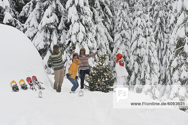 Österreich  Salzburg  Männer und Frauen beim Tanzen am Weihnachtsbaum im Winter