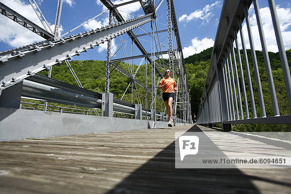 Woman runs across a steel bridge.