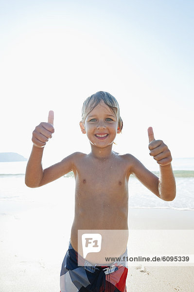 Portugal  Boy showing thumbs up  standing on beach