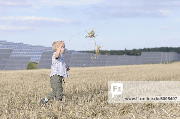 Boy running in grass  solar panels in background