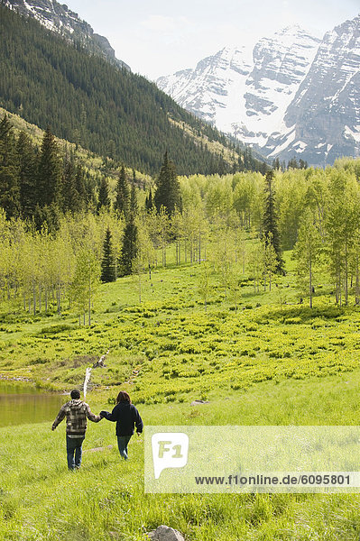 A couple walks across a field near the Maroon Bells in Aspen  CO.