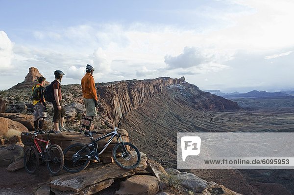 Three young men overlook a canyon after biking up the Amasa Back Trail  Moab  UT.