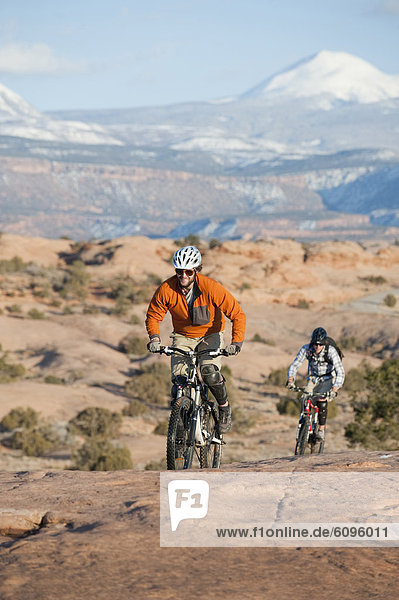 Two young men ride their mountain bikes on the Slickrock Trail  Moab  UT.