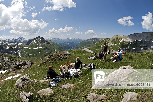 A group of hikers take a rest high above alpine glaciers and lakes in the Swiss Alps.