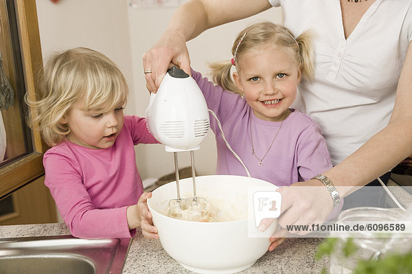 Mother and daughter mixing batter with electric whisk