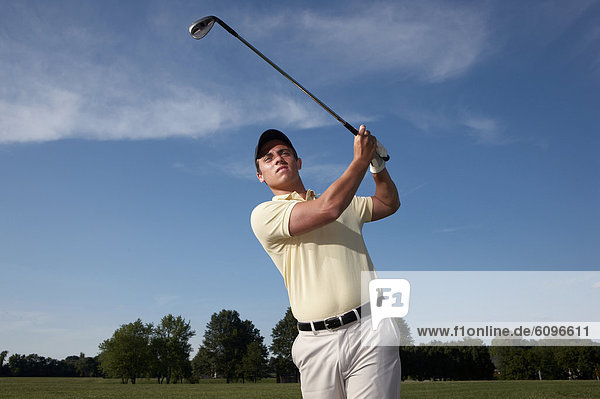 A male golfer swinging his club.