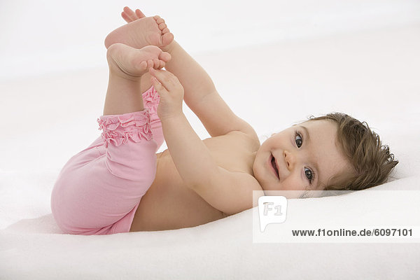 Baby girl lying on back and holding toes  smiling