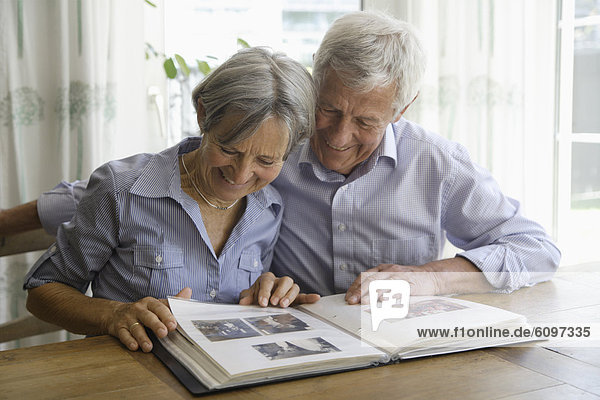 Germany,  Bavaria,  Senior couple with photo album,  smiling