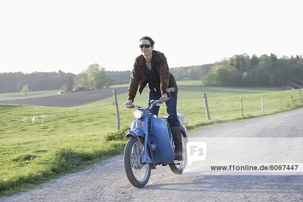 Mature woman riding old moped of 1960s