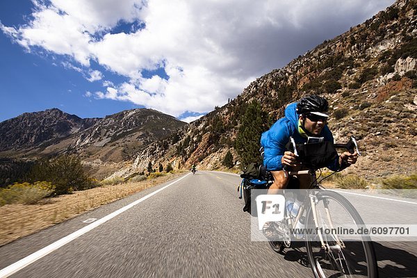 A male cyclist rides a loaded touring bike down the Tioga Pass in Yosemite  California.