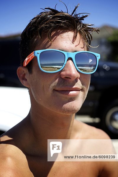 Portrait of male surfer wearing colorful sunglasses.