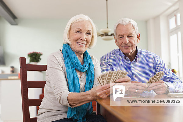 Senior Mann und Frau beim Kartenspielen  lächelnd  Porträt