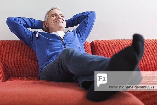 Senior Mann entspannt auf der Couch  lächelnd