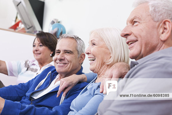 Senior men and women sitting on couch smiling