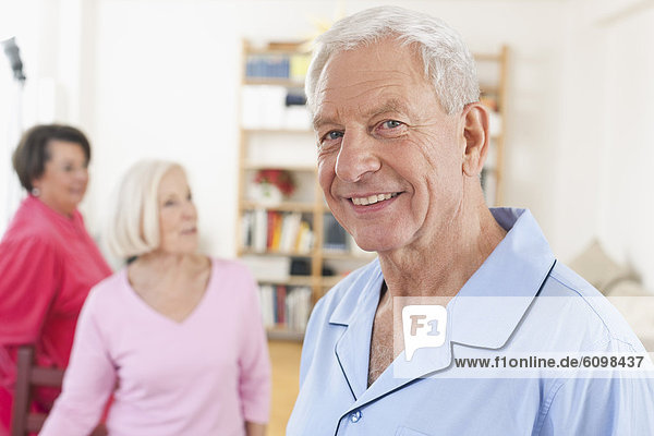 Senior man smiling  women standing in background