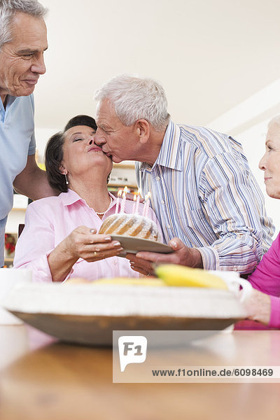 Ältere Männer und Frauen  die Geburtstag feiern  Mann  der sich an Frau küsst