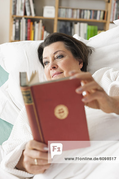 Seniorin auf dem Krankenbett liegend  Lesebuch