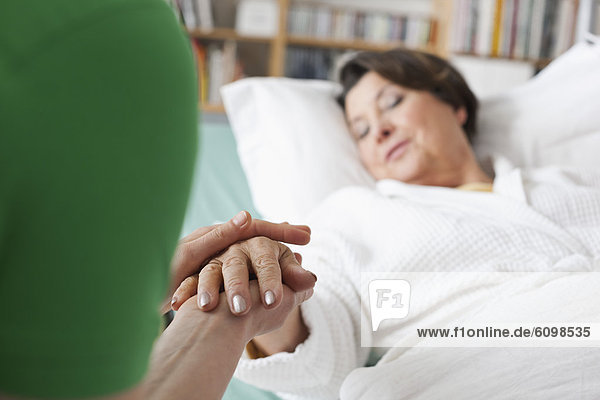 Mid adult woman holding hand of senior woman