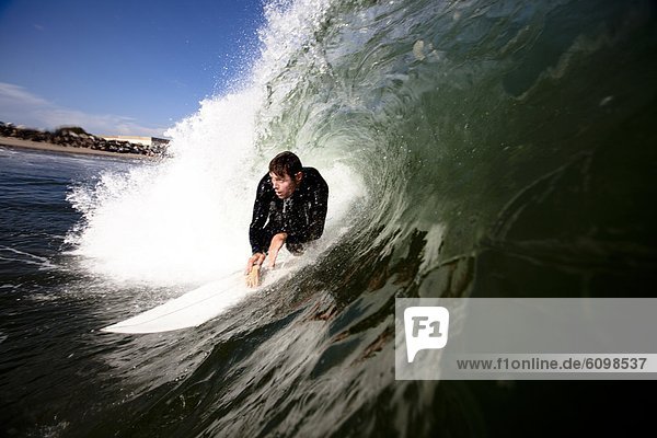 A male surfer comes out of a barrel.