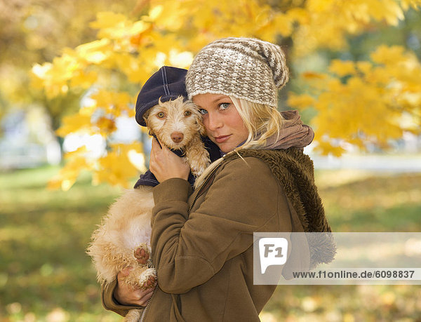 Austria  Young woman holding dog in autumn  portrait  close up