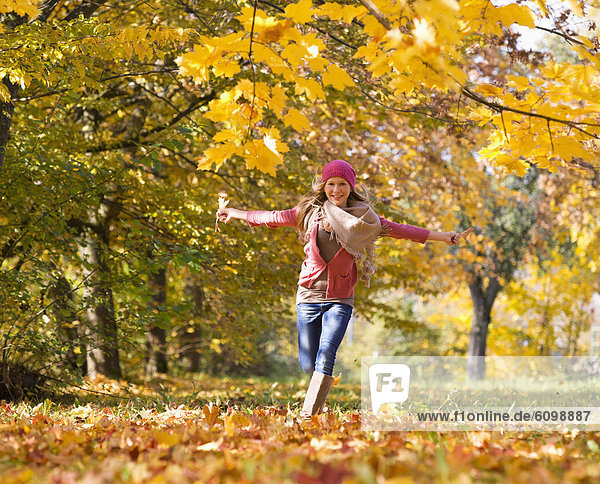 Österreich  Teenagermädchen auf Herbstblatt laufend