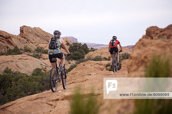 Two women mountain bike one of the Slick Rock routes in Moab Utah.