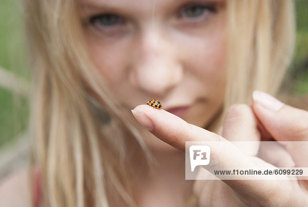 Austria  Teenage girl looking at ladybird on her finger