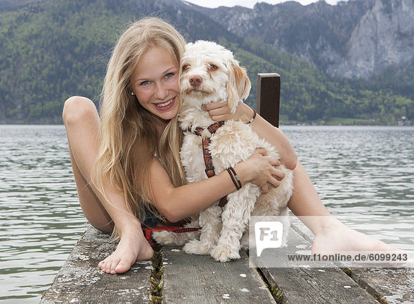 Österreich  Teenagermädchen mit Hund am Steg  lächelnd  Portrait