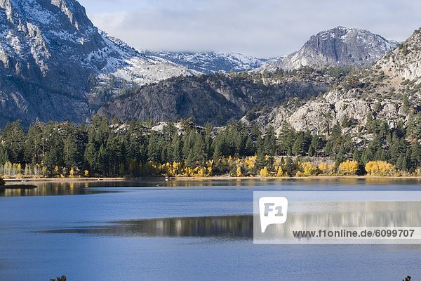 Two fishermen in a boat on a mountain lake with autumn leaves in the Sierra mountains of California