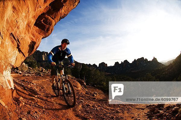 A man taking a bike ride on a rocky trail.