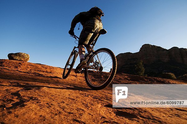 A middle age man rides his mountain bike through the red rock country of Sedona  AZ.