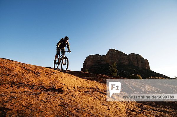A middle age man rides his mountain bikes through the red rock country of Sedona  AZ.