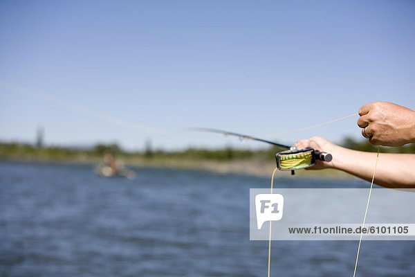 A short focus view of a fly fishing cast with the Snake River in the background.