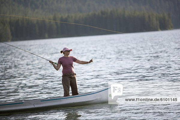 A woman casts her flyline while on a canoe.