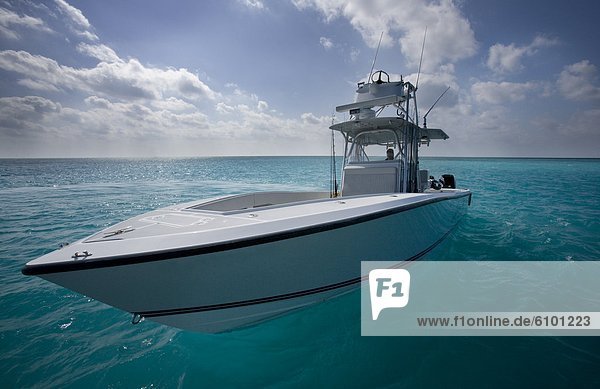 The bow of a streamlined fishing boat points toward the camera with blue water and clouds filling the frame.