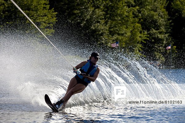 A female water skier rips a turn causing a huge water spray while skiing on Cobbosseecontee Lake near Monmouth  Maine.