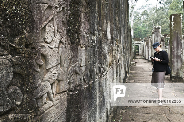 Woman traveller reading a guidebook at Angkor Wat  Cambodia.