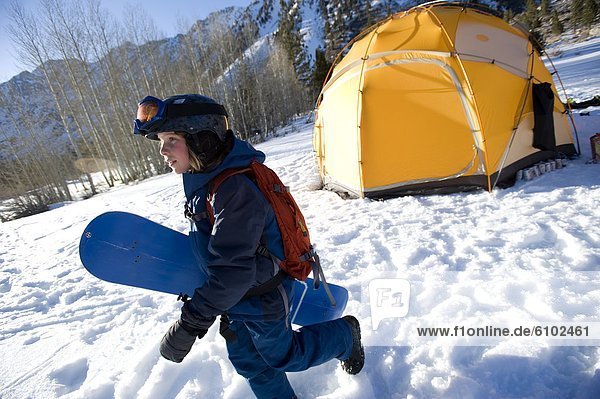 A boy gets ready to snowboard in the California backcountry.