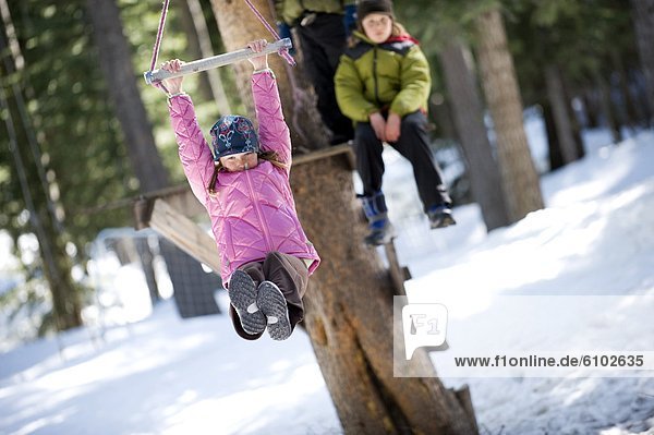A boy and girl zipline over snow in Lake Tahoe  California.