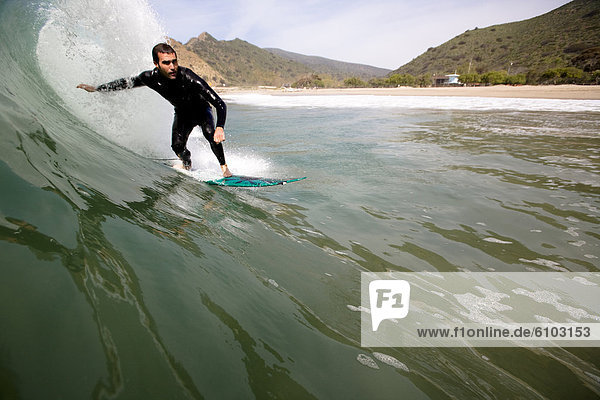 A surfer does a bottom turn while surfing in Malibu  California.