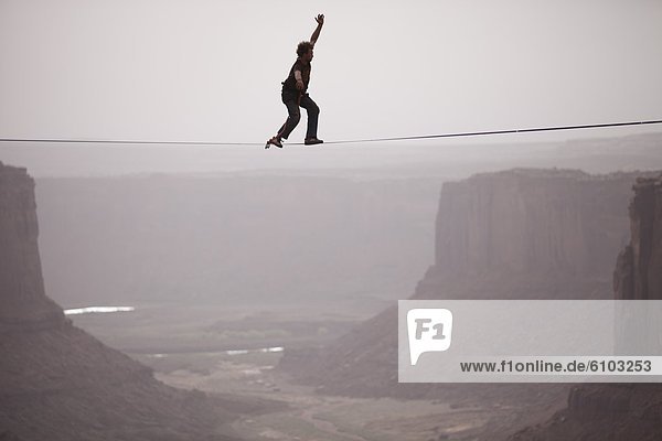 Andy Lewis working on a world record highline  three hundred and forty feet long  at the Fruit Bowl in Moab  Utah  USA.
