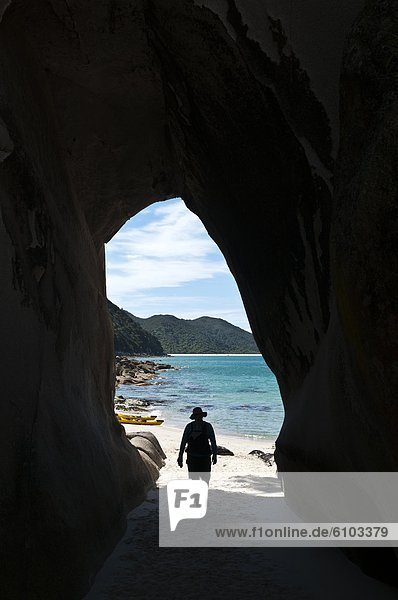 Woman sea kayaker and granite arch  Abel Tasman National Park  Nelson  New Zealand.