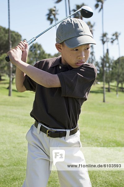 A young boy golfing at a golf course in Los Angeles  California.