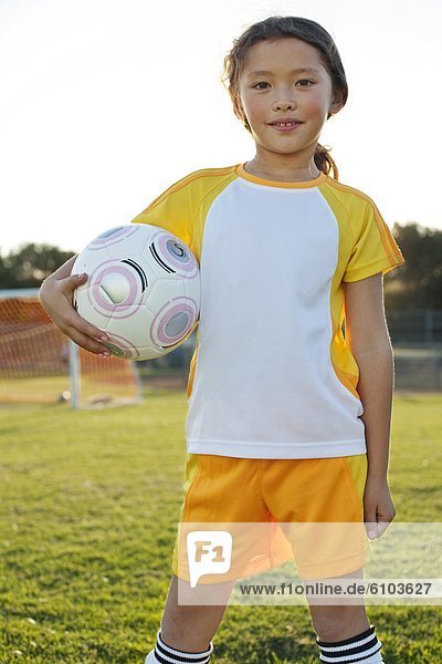 A young girl posing with her soccer ball on a soccer field in Los Angeles  California.