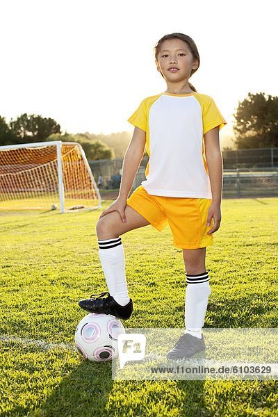 A young girl posing with her soccer ball on a soccer field in Los Angeles  California.++