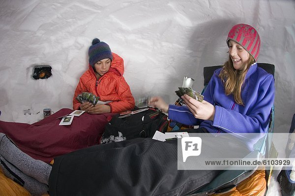 Boy and girl playing cards in snow cave  Silverton  Colorado.