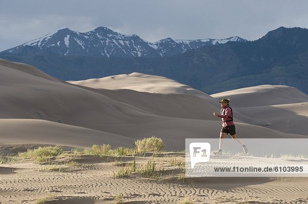 Woman running through sand dunes  Great Sand Dunes National Park  Alamosa  Colorado.