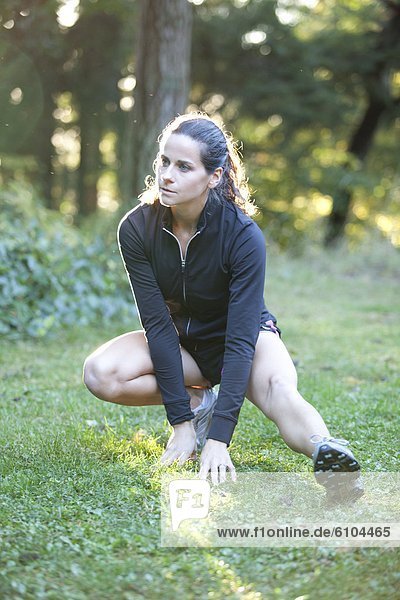 A young woman stretches before a run at Point Defiance Park.